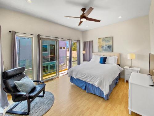 a bedroom with a bed and a chair and windows at Ostend Escape - Multiple Patios, Large Rooftop, Water Views, Garage & Fast Wifi in San Diego