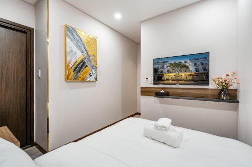 1 dormitorio con 1 cama blanca y TV en la pared en VIN HOTEL en Vĩnh Long