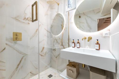 une salle de bain avec un lavabo blanc et un miroir dans l'établissement Villa Caron - Appartements haut de gamme avec chambre hyper centre, à Rouen