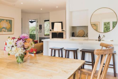 a kitchen and living room with a vase of flowers on a table at The Cottage at Bolobek in Macedon