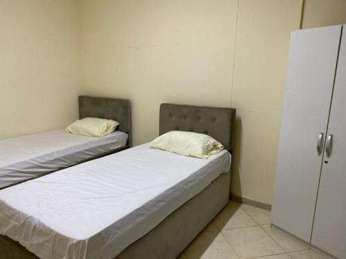 two twin beds in a room with a closet at Provis for family in Sharjah