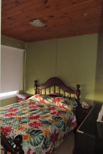 1 dormitorio con 1 cama con colcha de flores en Casa en Quequén hasta 5 personas en Quequén