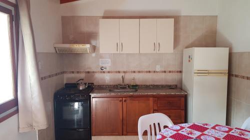 a kitchen with a stove and a sink and a refrigerator at Departamenos Minsu in Valle Hermoso
