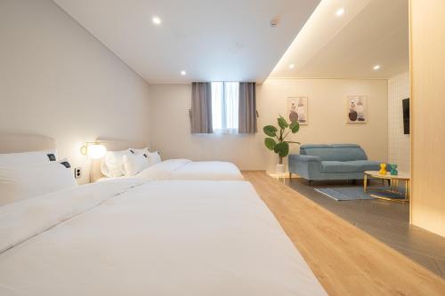 a bedroom with a large white bed and a blue couch at Browndot Gangneung Station in Gangneung
