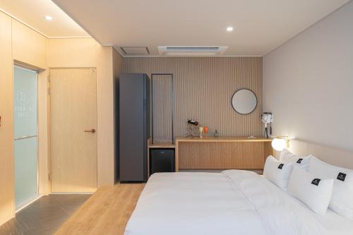 a bedroom with a large white bed with white pillows at Browndot Gangneung Station in Gangneung