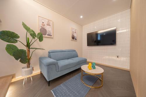 a living room with a blue couch and a tv at Browndot Gangneung Station in Gangneung