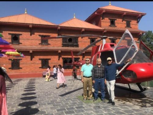 un grupo de personas de pie junto a un helicóptero rojo en Captain’s Sky ( Special Resort) en Bahāsi