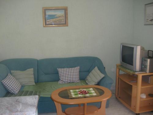 sala de estar con sofá azul y TV en Apartments by the sea Privlaka, Zadar - 22380, en Privlaka