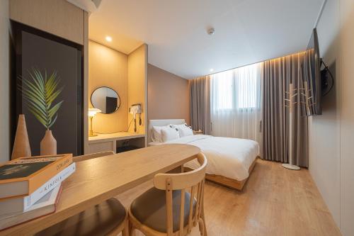 a hotel room with a bed and a desk with a desk at Browndot Gangneung Station in Gangneung