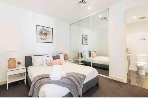 a white bedroom with a bed and a bathroom at Bright City Views Melbourne Central Penthouse on Collins in Melbourne