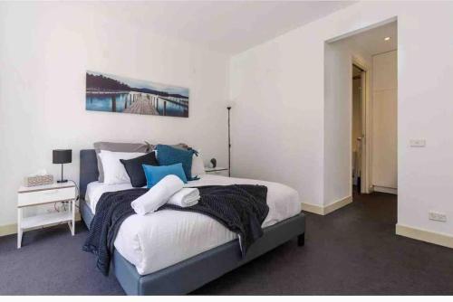 a bedroom with a large bed with blue pillows at Bright City Views Melbourne Central Penthouse on Collins in Melbourne