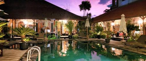 a swimming pool in a resort with chairs and trees at Stana Puri Gopa Hotel in Sanur