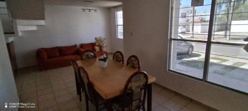 a dining room with a table and chairs and a couch at Casa Gerbera Queretaro in Querétaro
