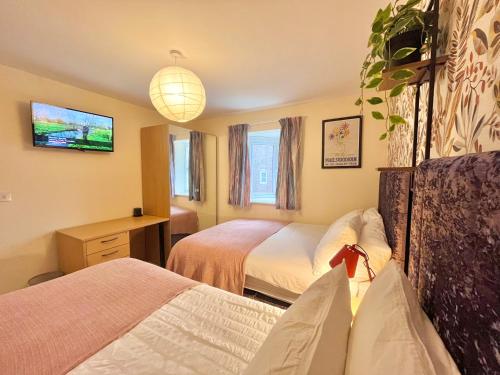 a hotel room with two beds and a tv at Payler House Sheffield-WiFi -Large Parking Space-cozy 4 bedrooms in Sheffield