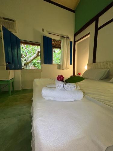 een slaapkamer met 2 bedden, handdoeken en een raam bij Pousada Marina de Boipeba in Ilha de Boipeba