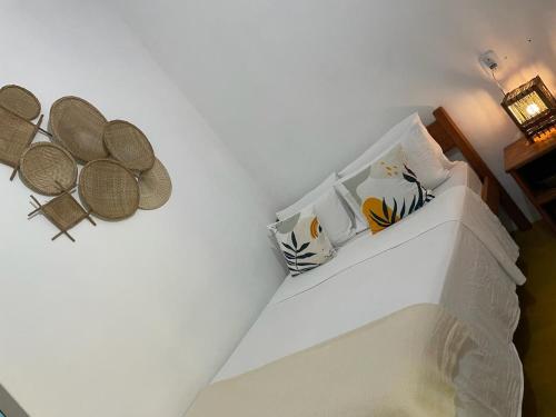 a bedroom with a white wall with rattan baskets at Pousada Lumar in Caraíva