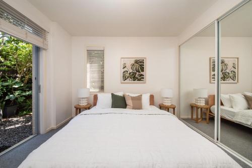 a bedroom with a large white bed and a window at Heart of Hampton by the Beach in Melbourne