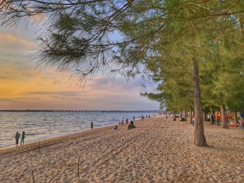 una playa con un grupo de personas y árboles en ella en Mutiara Melaka Beach Resort by Glex, en Tangga Batu