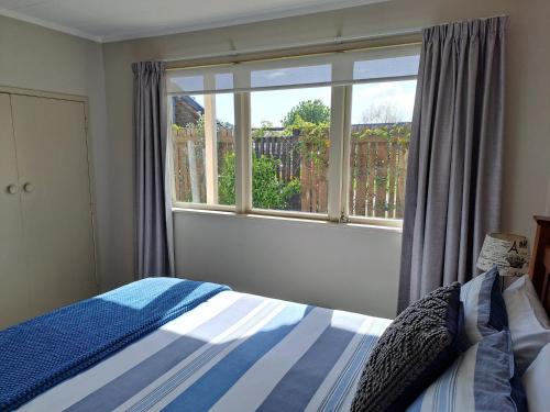 een slaapkamer met een bed en een groot raam bij Feel at Home in Tauranga