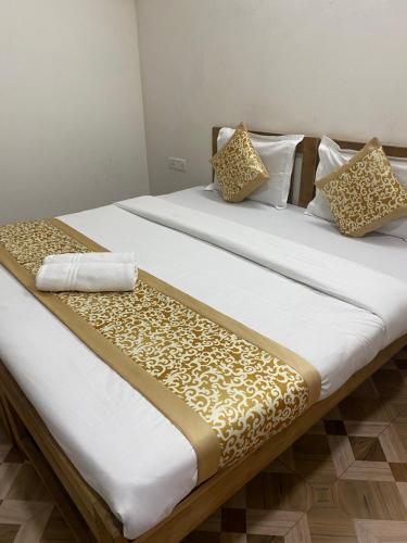 two beds with white and gold sheets and pillows at Calangute Beach Palms in Calangute