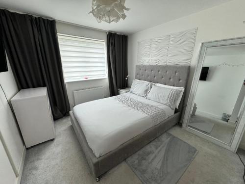 a bedroom with a large bed and a mirror at Modern 2 bed city apartment with private parking in Swansea