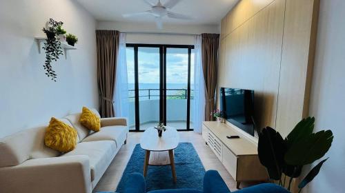 a living room with a couch and a tv at Mutiara Melaka Beach Paradise by Glex in Tangga Batu