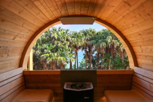 an arched window in a tiny house with palm trees at 泊まれるアートミュージアム 琉球ヴィラ in Tatsugo