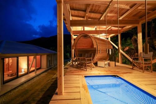 una terraza al aire libre con piscina y una casa en 泊まれるアートミュージアム 琉球ヴィラ en Tatsugo