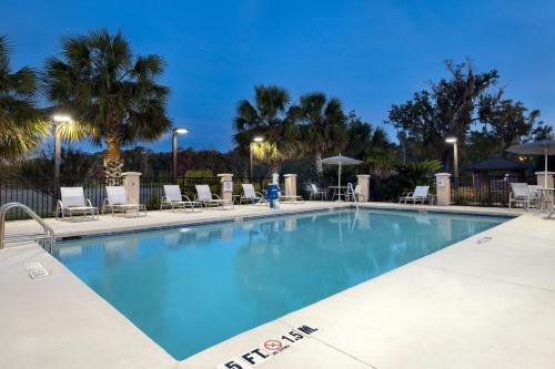 a large swimming pool with chairs and palm trees at Staybridge Suites Tallahassee I-10 East by IHG in Tallahassee