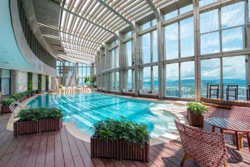 a large swimming pool in a building with windows at Hyatt Place Sanya City Center in Sanya