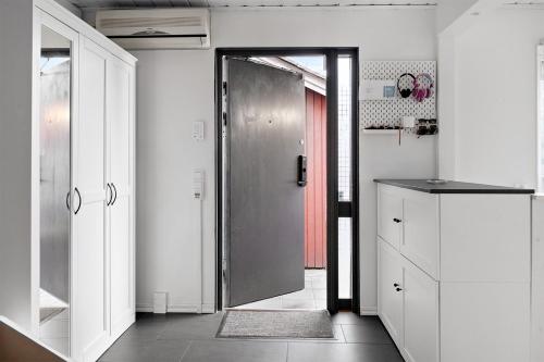 uma cozinha com uma porta que conduz a uma cozinha com armários brancos em Radhus med 5 min bilavstånd till centrum & strand em Halmstad