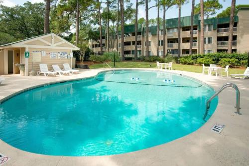 a large pool with chairs and a building in the background at Tranquility By The Beach 1st Fl Sleeps 6,king Bed in Hilton Head Island