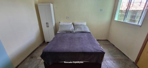 a bedroom with a bed with a purple blanket on it at Temporada em família e amigos. in Barra do Garças
