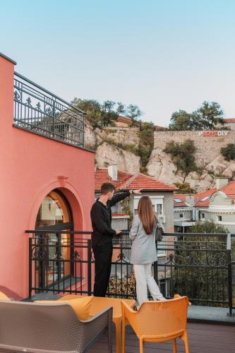 a man and a woman standing on a balcony at Villa Flavia Heritage Boutique Hotel in Plovdiv