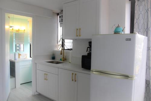 a kitchen with white cabinets and a white refrigerator at Hawaiian Monarch 1611 condo in Honolulu
