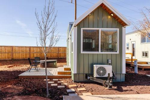 a green tiny house with a table and a window at Zion Tiny Home, Hot Tub, Red Rock Views in Apple Valley