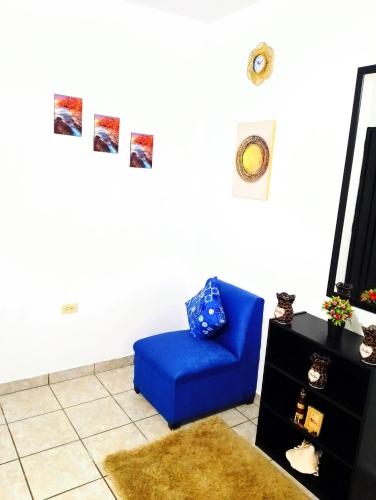 ein Wohnzimmer mit einem blauen Stuhl und einem TV in der Unterkunft MI HOGAR in Tegucigalpa