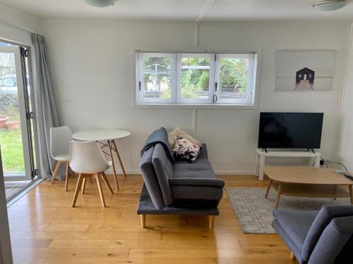 a living room with a chair and a tv and a table at Tranquil Nest Escape with deck and garden in Auckland