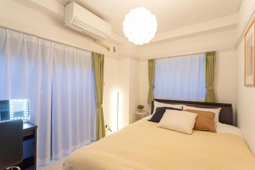 a bedroom with a bed and a chandelier at Kamata Smile House - 蒲田すまいるハウス in Tokyo