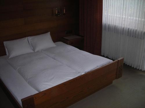 a large bed with white sheets and a wooden frame at Landhaus zum Griena in Mayrhofen