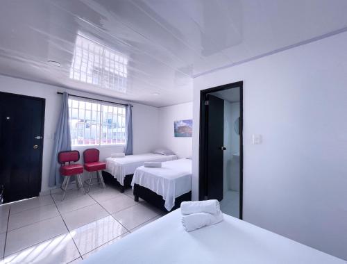 - une chambre avec deux lits et deux chaises rouges dans l'établissement Island Vibes, à San Andrés