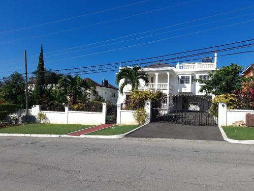 a white house with a fence and a street at Melrose Place in Montego Bay