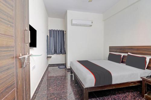 a bedroom with a bed and a television and a door at 80977E SS Metro Ritz in Ameerpet