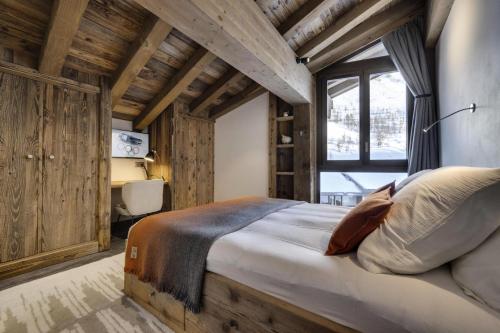 ein Schlafzimmer mit einem großen Bett in einem Zimmer mit Holzwänden in der Unterkunft Residence La Canadienne - 5 Pièces pour 8 Personnes 554 in Val dʼIsère