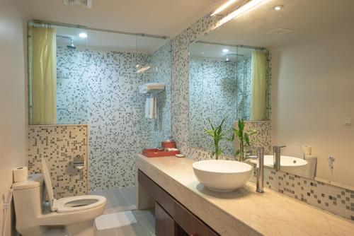 uma casa de banho com um lavatório, um WC e um espelho. em Central Mansions Serviced Apartments em Phnom Penh
