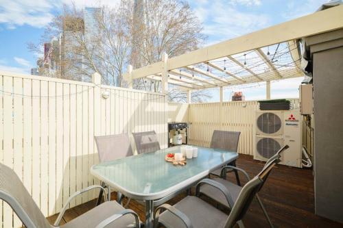 a table and chairs on a patio with a fence at Water front - KING 3 Room Rooftop The Rocks #E2 in Sydney