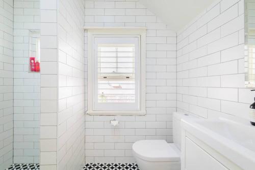 a white bathroom with a toilet and a window at Water front - KING 3 Room Rooftop The Rocks #E2 in Sydney