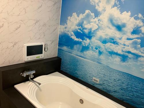 a bathroom with a bath tub with a tv on the wall at Aegean Sea-Adults Only in Shizuoka