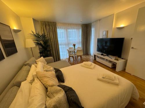 a large white bed in a room with a television at Luxury Apartment in Canary Wharf in London