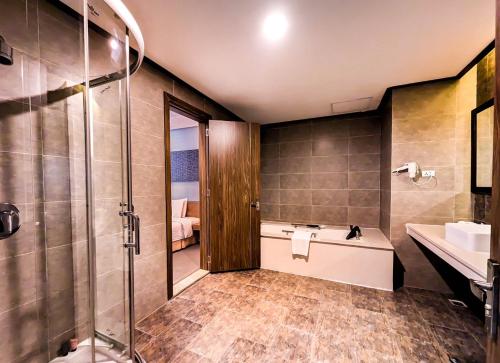 a bathroom with a shower and a sink and a tub at Muong Thanh Grand Xa La Hotel in Hanoi